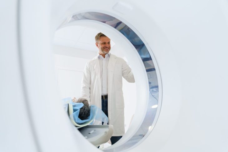 Radiologist controls MRI or CT Scan with patient undergoing procedure. High Tech medical equipment